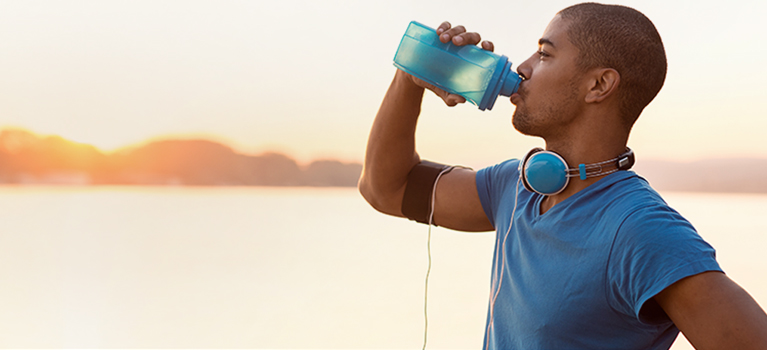 Man drinking water by a lake